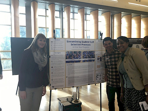 FYP professional staff standing in front of a poster board with information about the student staff application process