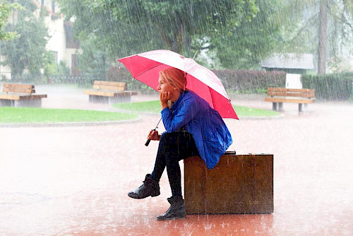 woman sitting with a red umbrella in the rain
