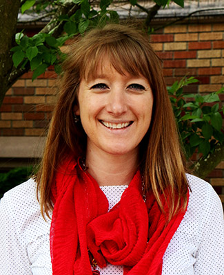 Ali Albrecht, a woman wearing a red scarf and white and black polka dot shirt smiling